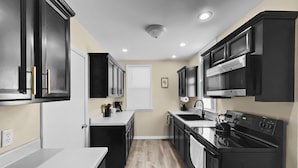 A modern kitchen with black cabinets, a stainless steel stove, and a white countertop. - Grand Lodge Pet-Friendly Home w/ Workspace (Grand Junction)