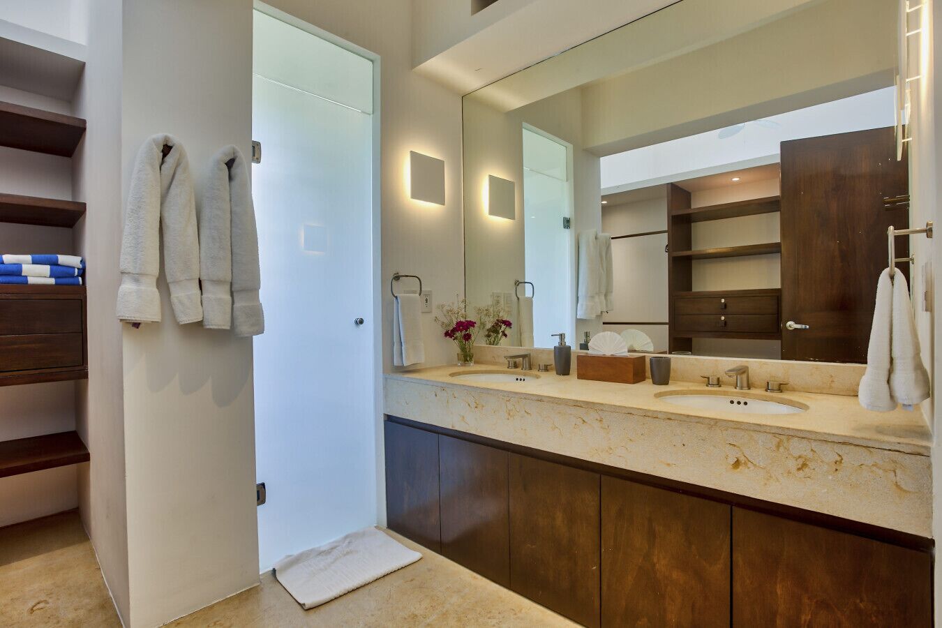 A modern bathroom with a large mirror, dual sinks, and dark wooden cabinets.