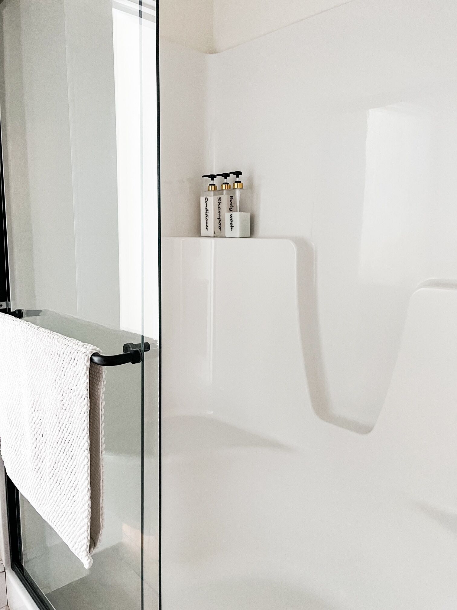 Une salle de bain moderne avec une douche à parois de verre, une baignoire blanche et un porte-serviettes avec une serviette blanche.