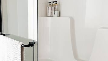 Une salle de bain moderne avec une douche à parois de verre, une baignoire blanche et un porte-serviettes avec une serviette blanche.