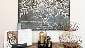 Een eettafel met een kookboek, een metalen kan en een draadmand.