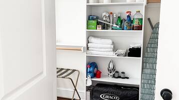 Ein ordentlich organisierter Kleiderschrank mit Regalen, die Handtücher, Reinigungsmittel und eine Graco-Tasche beherbergen.