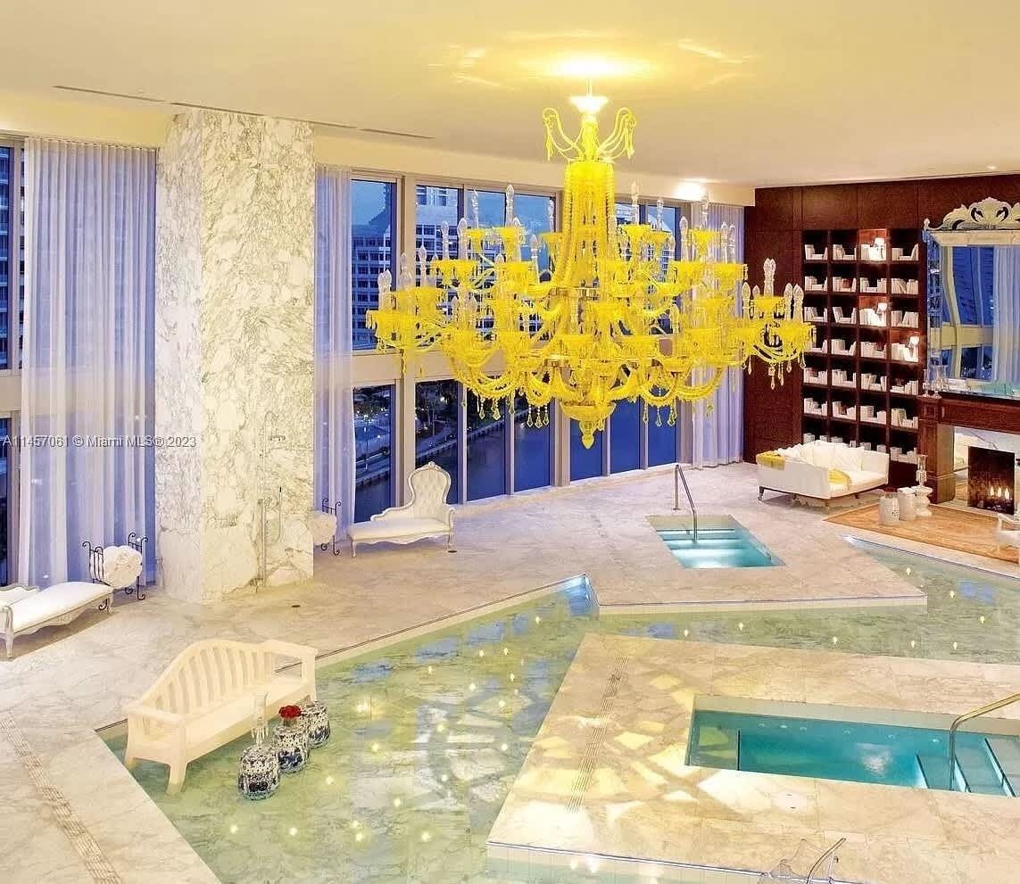 Ein luxuriöses Interieur mit einer großen Chandelier, einem Poolbereich und einem Kamin.