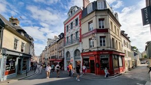 Une rue bordée d’immeubles, dont une chocolaterie et un café.