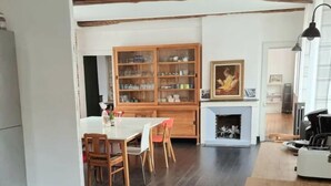 A dining area with a wooden table and chairs, a cabinet with glass doors, and a fireplace. - Kinta Panda 🐼 | Pool Table | City Center | 13 + 2 guests (Honfleur)