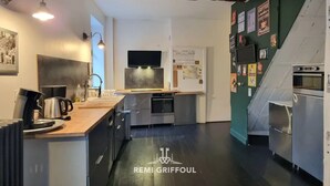 A modern kitchen with a wooden countertop, stainless steel appliances, and a green accent wall. - Kinta Panda 🐼 | Pool Table | City Center | 13 + 2 guests (Honfleur)