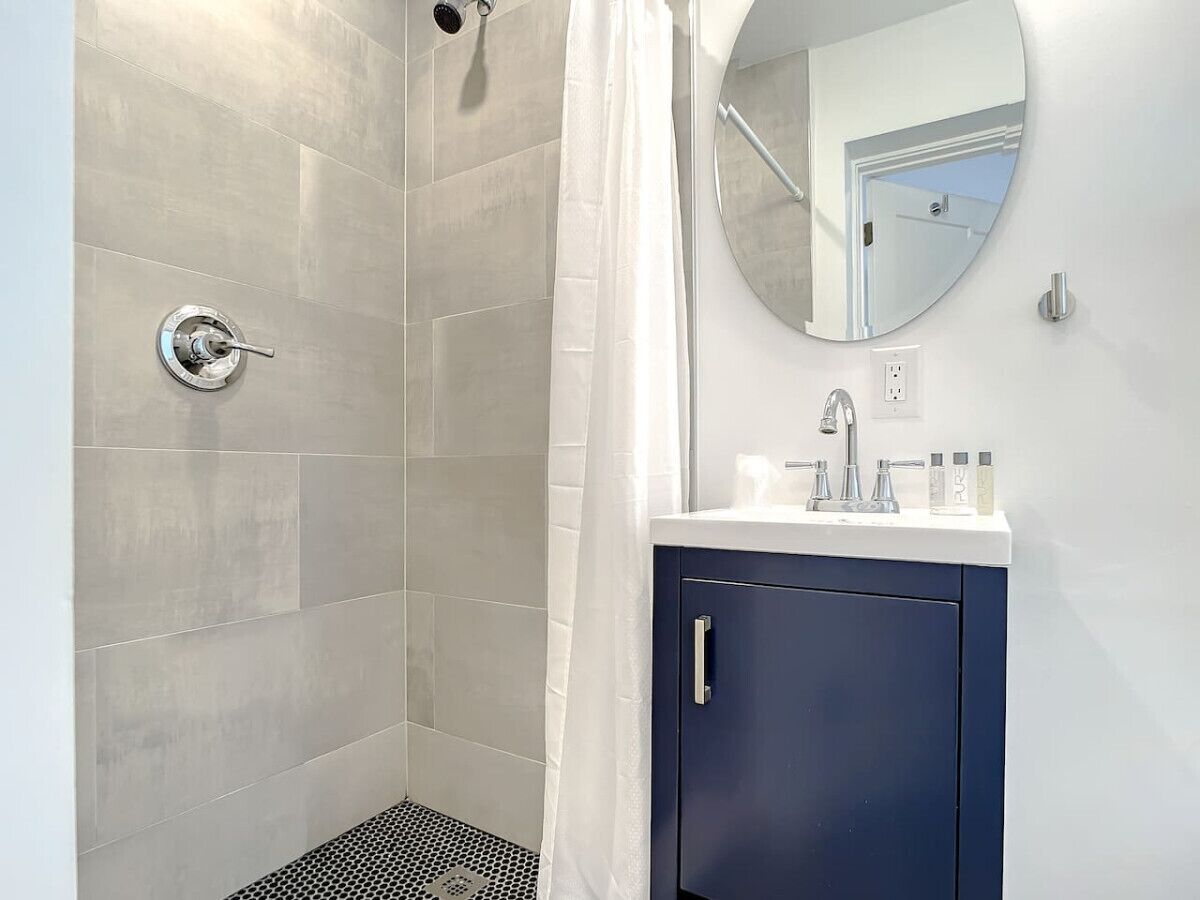 Une salle de bain avec une douche, un lavabo équipé de produits de toilette et un miroir.