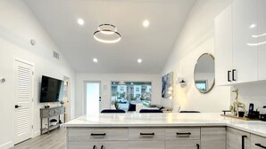 Une cuisine moderne dotée d’un grand îlot central, de meubles blancs et d’un téléviseur à écran plat.