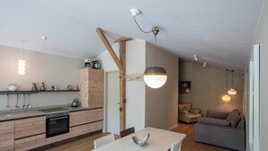 Een moderne keuken met houten kastjes, een ingebouwde oven en een eethoek met een witte tafel en stoelen.