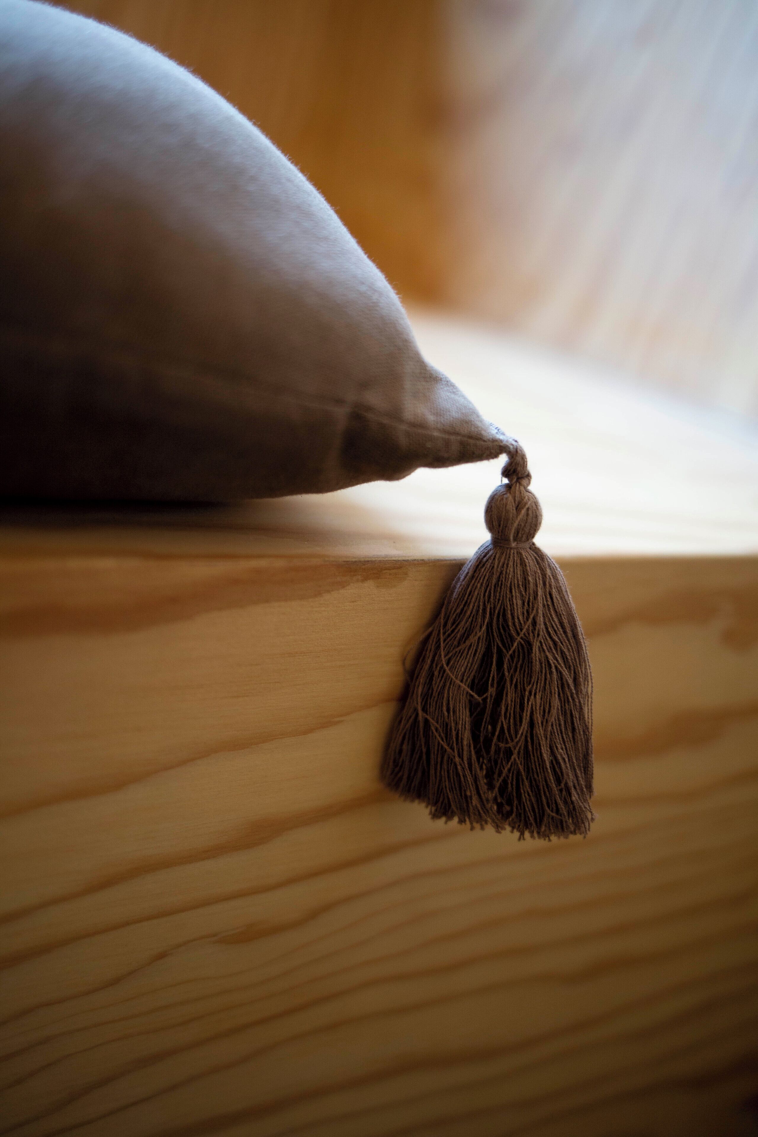 Un gros plan d’une surface en bois avec un coussin et une frange.