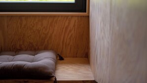Een kamer met een raam, een bed en een houten vloer.