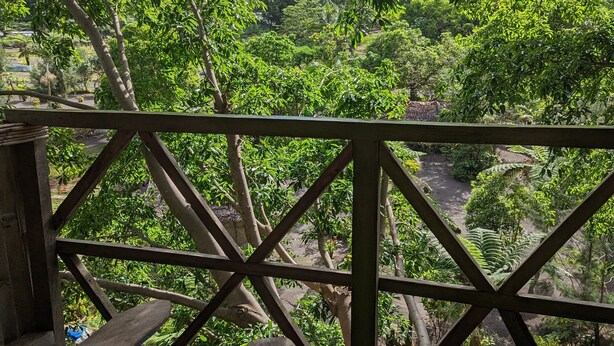 Una terraza de madera con vistas a un paisaje exuberante y un monte a lo lejos.