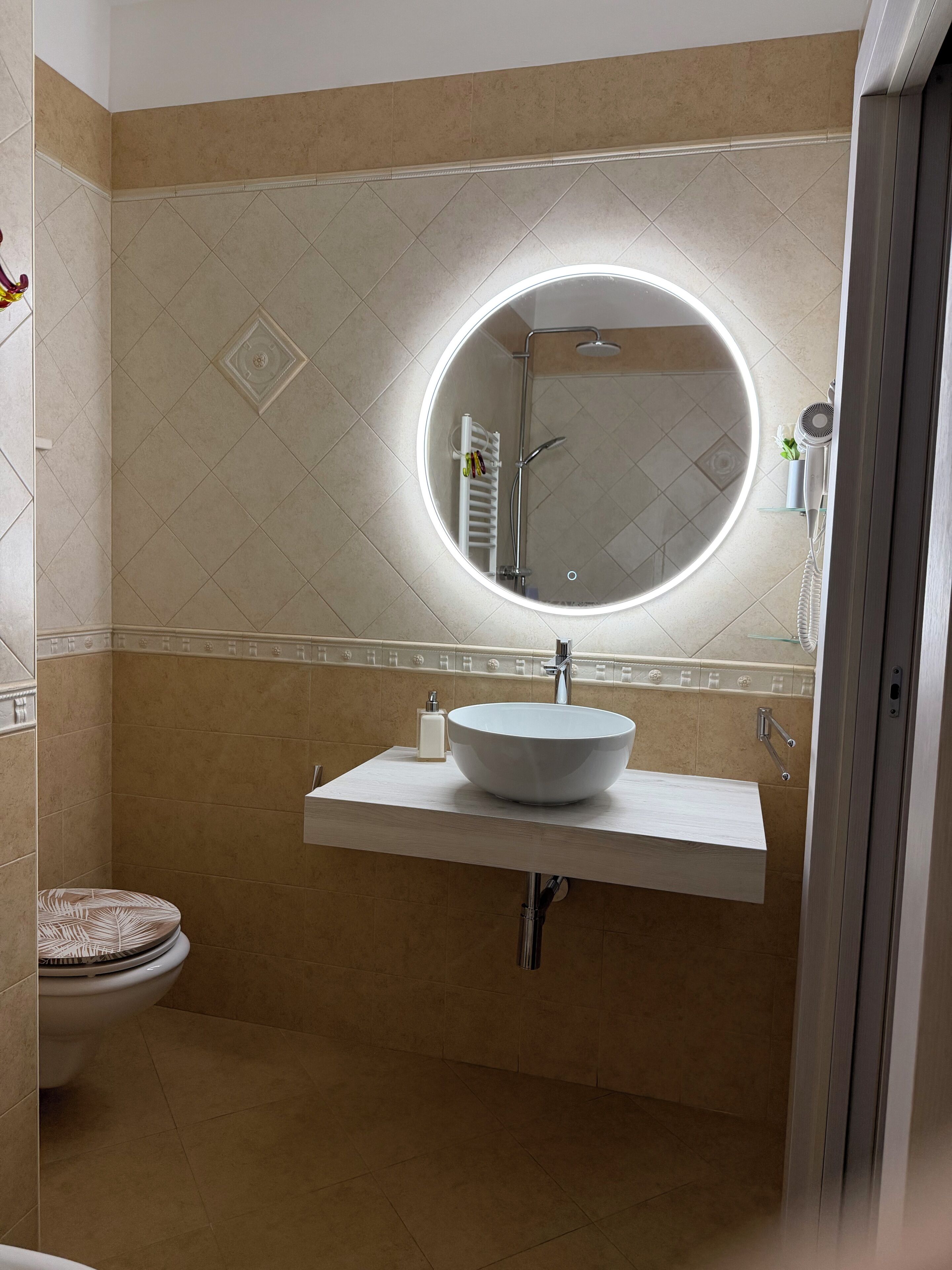 A bathroom with a round mirror, a white sink, and a toilet.