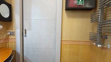 A bathroom with a white sink, a bidet, a mirror, and a wall-mounted TV.