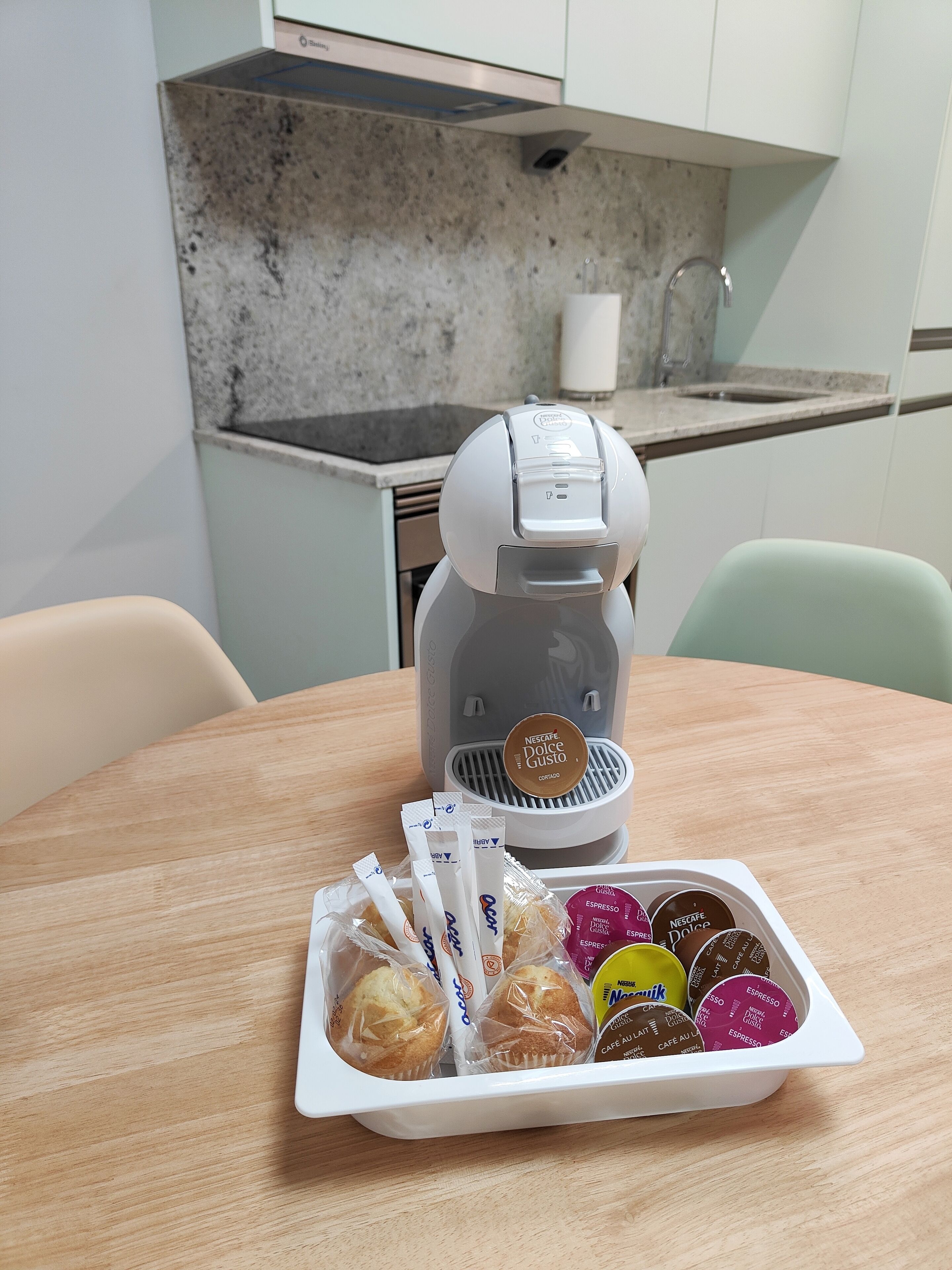 Una cocina con una cafetera y una bandeja de cápsulas de café.