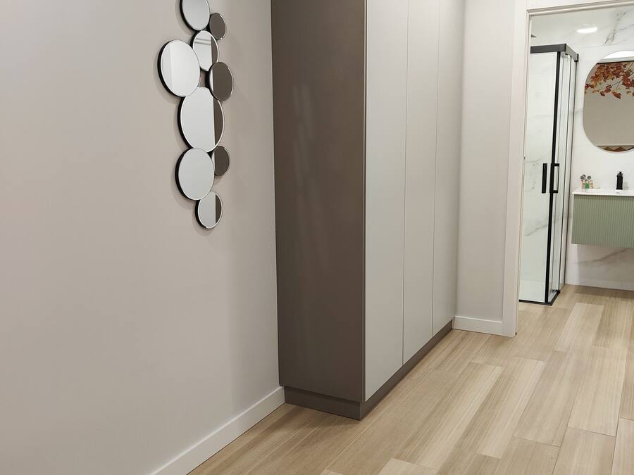 Un pasillo moderno con un armario, un revestimiento de espejo decorativo y un baño con lavabo de mármol.