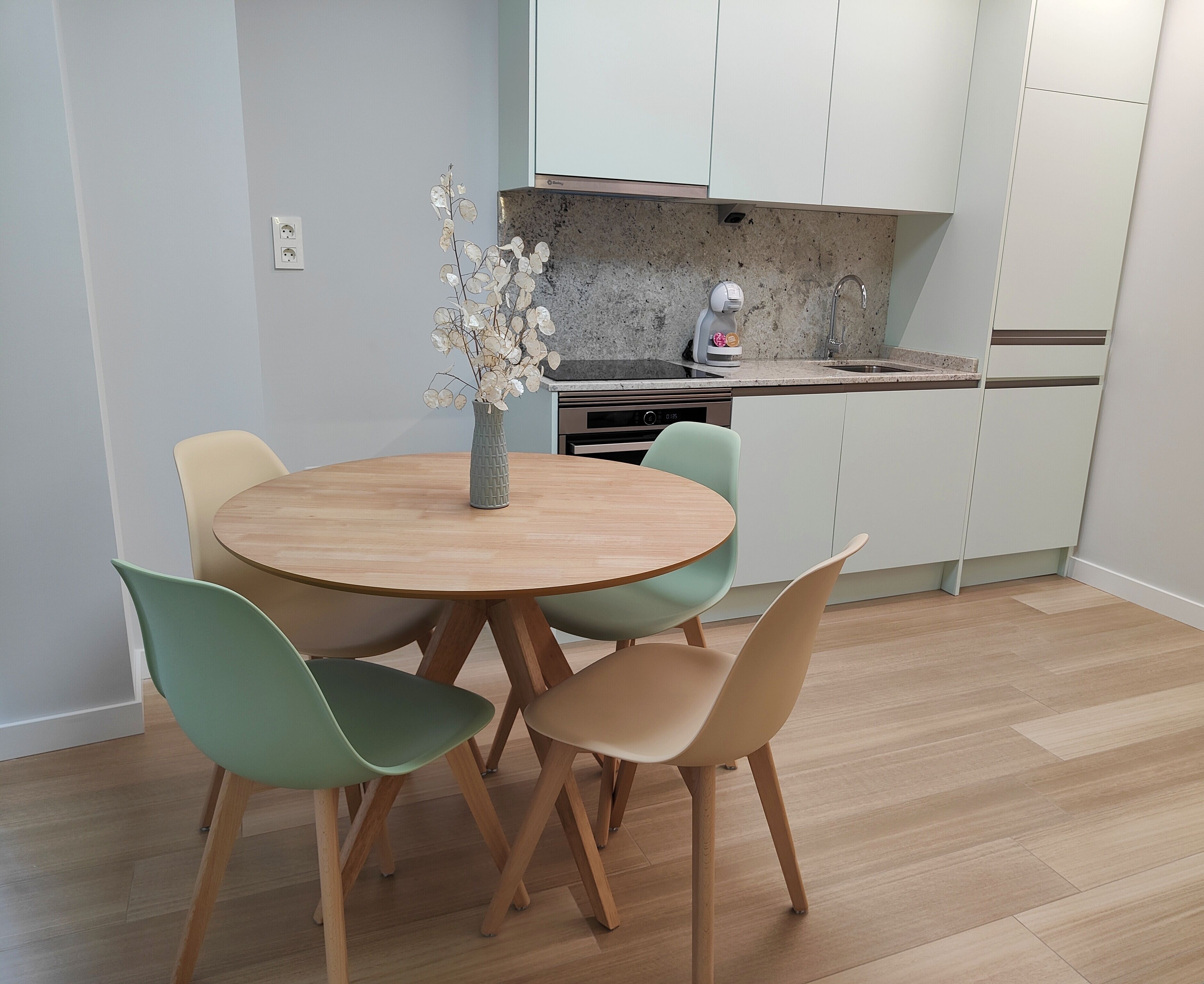 Una cocina moderna con armarios blancos, encimera de granito y lavavajillas integrado.
