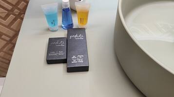 Een badkamer met een groot wastafel, een spiegel en toiletartikelen zoals zeep, shampoo en gel.
