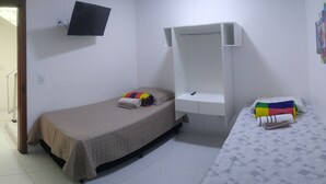 Ein Schlafzimmer mit zwei Betten, einem an der Wand befestigten Fernseher und einem kleinen Schreibtisch.