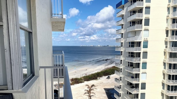 Um edifício alto com varandas com vista para a praia.