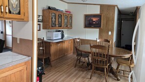 A compact kitchen with wooden cabinets, a microwave, and a dining table with chairs.