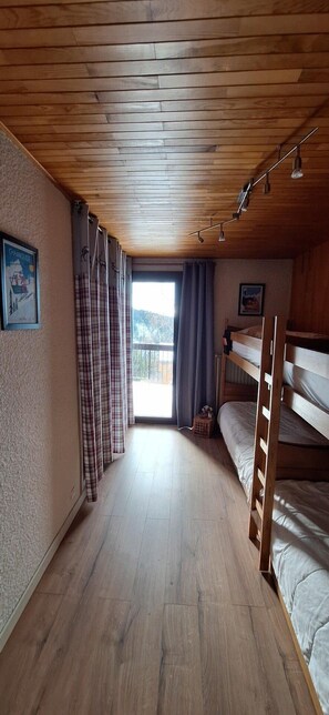 Cozy retreat with two beds, a wooden chest, and a mountain view.