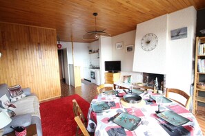 Relax in this inviting living room with a dining table, fireplace, and TV for a comfortable stay.