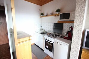 Compact kitchen with gas stove, microwave, oven, and dishwasher.