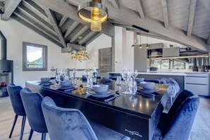 A modern dining area with a black table set for six, surrounded by blue chairs.