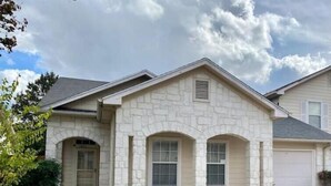 A two-story house with a stone facade, a front entrance, and a garage.