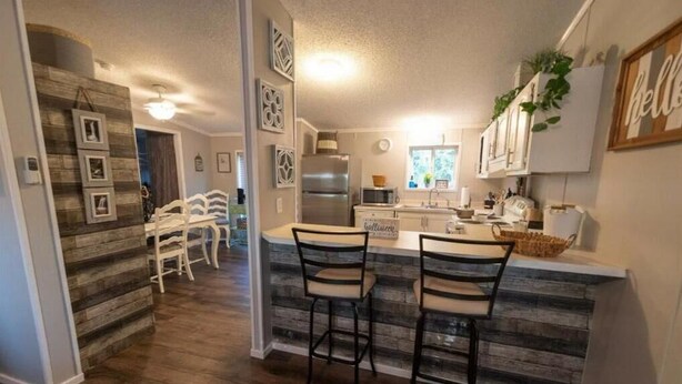 A modern kitchen with a central island, bar stools, and a dining area with a wooden table and chairs.