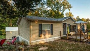 A small single-story house with a porch, a covered outdoor seating area, and a small deck.