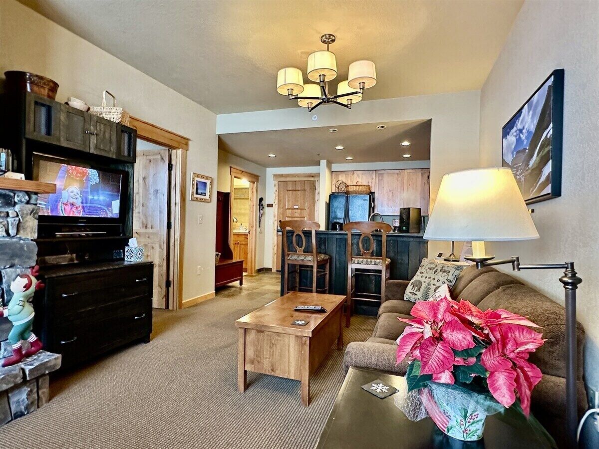 A cozy living room with a television, wooden furniture, and a potted plant.