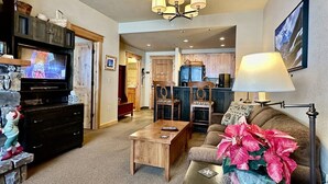 A cozy living room with a television, wooden furniture, and a potted plant.