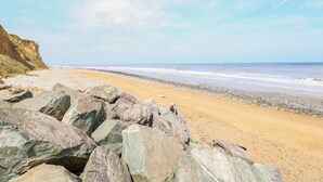 A beach with large rocks in the foreground and a clear sky.