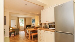 A modern kitchen with white cabinets, a stainless steel refrigerator, and a wooden dining table.