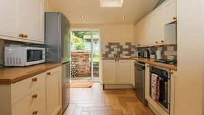 A kitchen with wooden flooring, white cabinets, a microwave, a stove, and a dishwasher.
