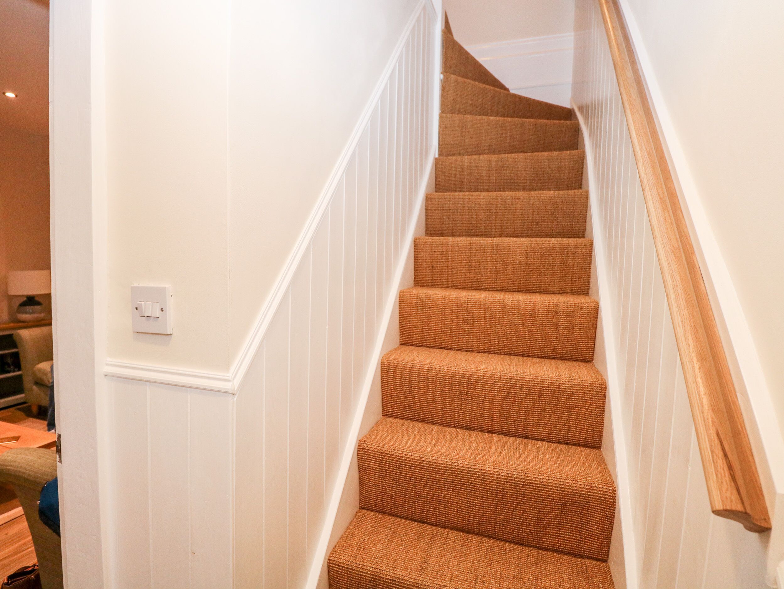 Un escalier avec des rampes en bois et des marches recouvertes de moquette.