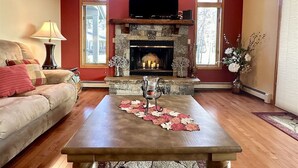 Una sala de estar con chimenea, un sofá, una mesa de centro y un televisor.