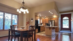 Una cocina amplia con armarios de madera, una isla central y un comedor con una mesa grande y sillas.