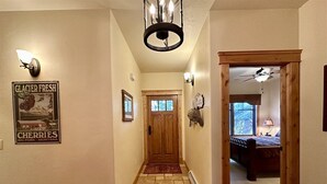Ein Korridor mit einer Holztür, einem Chandelier und einem Poster an der Wand.