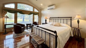 Ein Schlafzimmer mit einem großen Bett, einem Deckenventilator, einem Fenster mit Vorhängen, einem Schreibtisch und einem Stuhl.