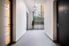 A corridor with a potted plant, a black door, and a view of a building in the background. - TELU City Center (Beograd)