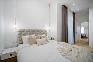 Ein modernes Schlafzimmer mit einem großen Bett, einem Kopfteil, Nachttischen und einem Beistelltisch.