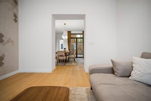 Una sala de estar moderna con un sofá, una mesa de centro de madera y un área de comedor al fondo.