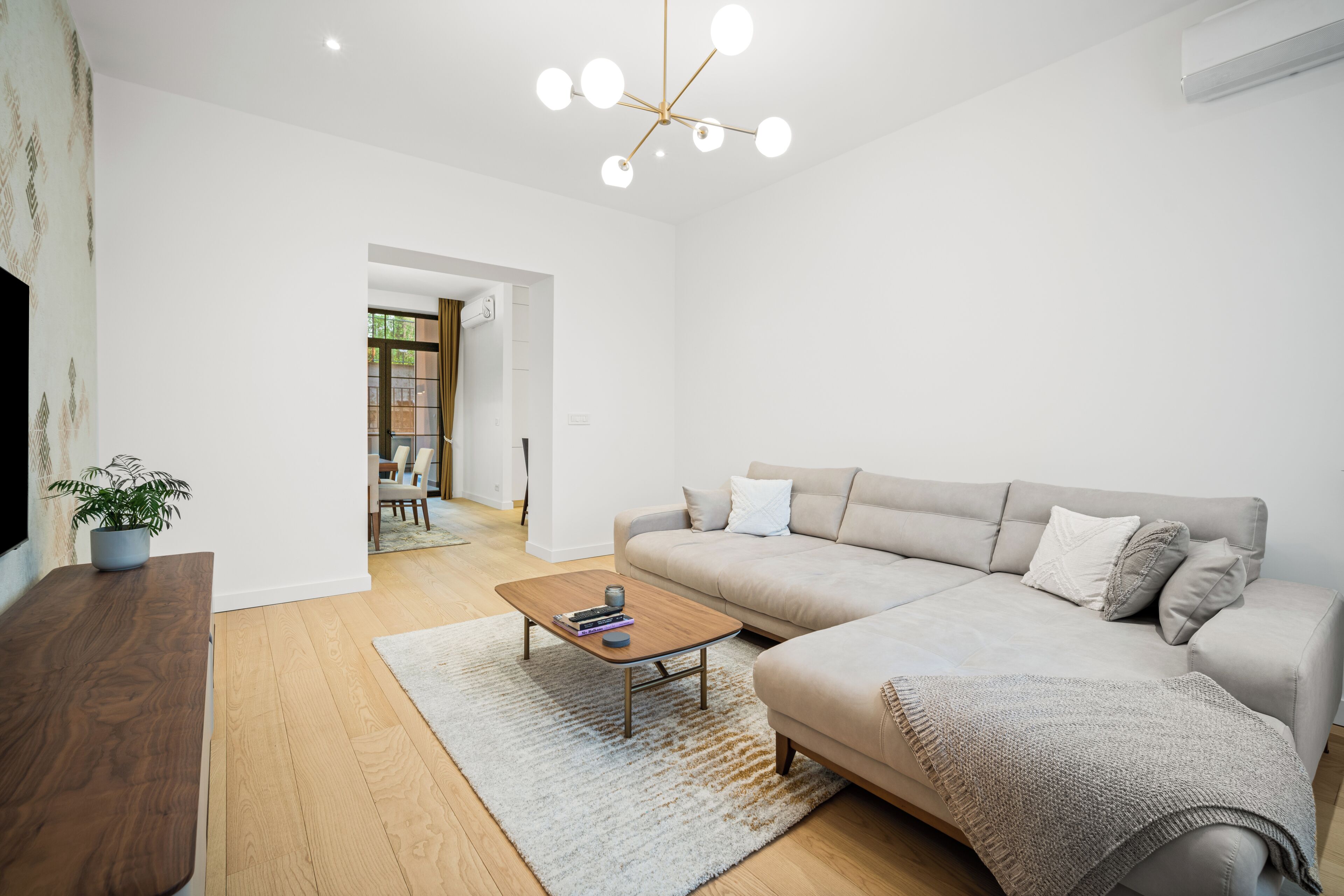 Una sala de estar moderna con un sofá, una mesa de centro y un televisor sobre un mueble de madera.
