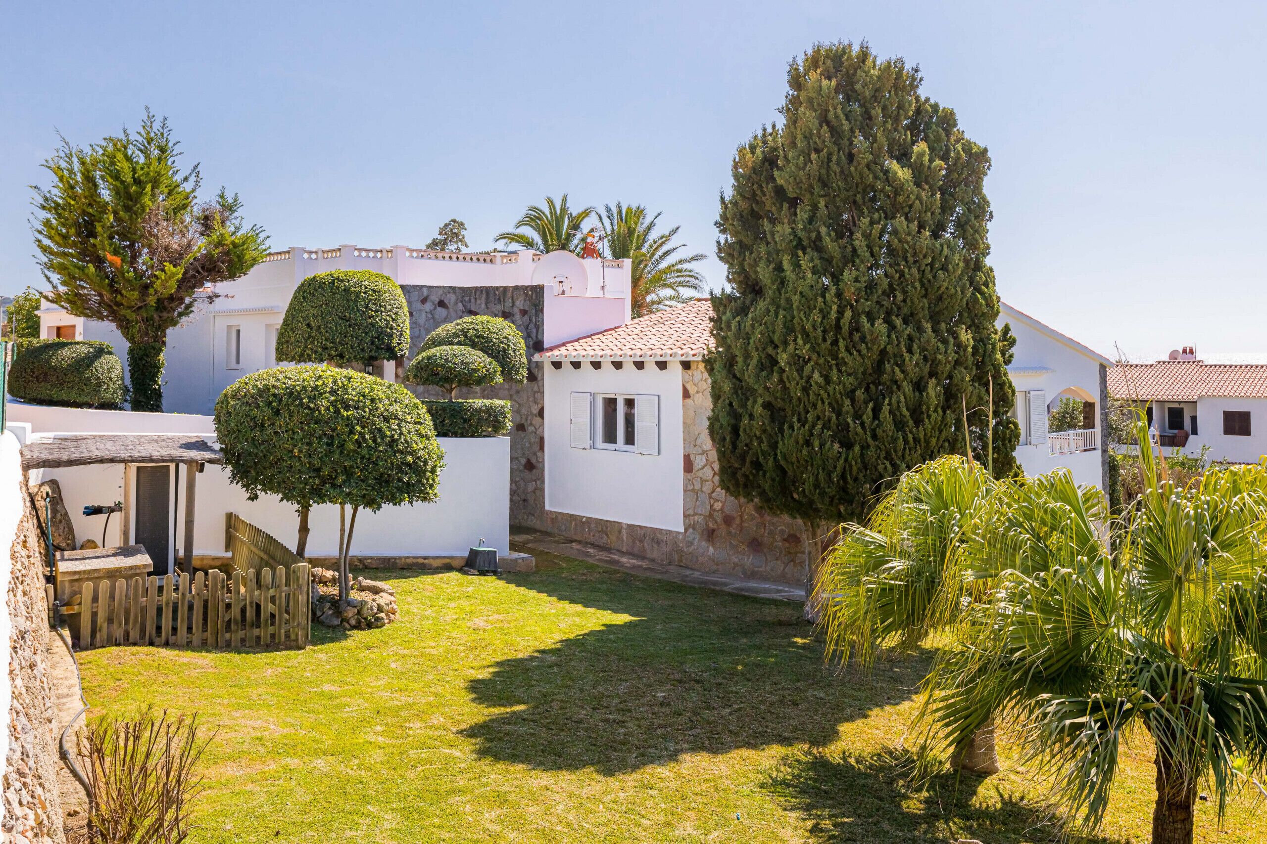Un giardino curato con siepi ordinate, un muro in pietra e diverse varietà di alberi.