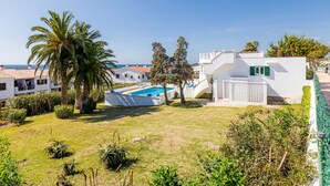 Una villa blanca con piscina, rodeada de vegetación y vista despejada al mar.