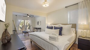 A bedroom with a bed, bedside table, and a desk with a chair.