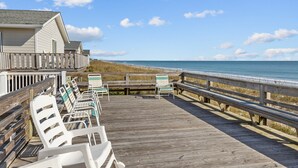 Une terrasse en bois avec des chaises de plage et vue sur l’océan.